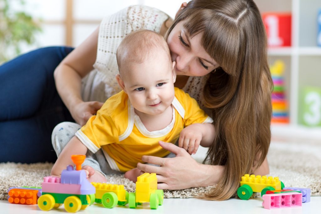 mother and baby boy play together with toys at home
