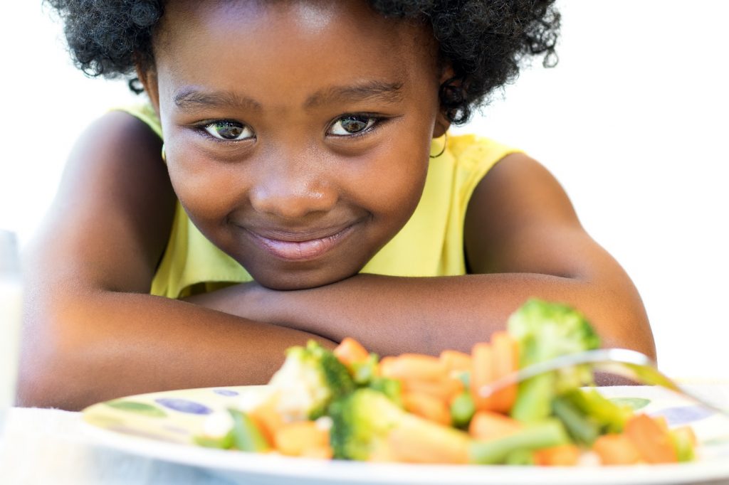 african girl in front of healthy vegetable dish