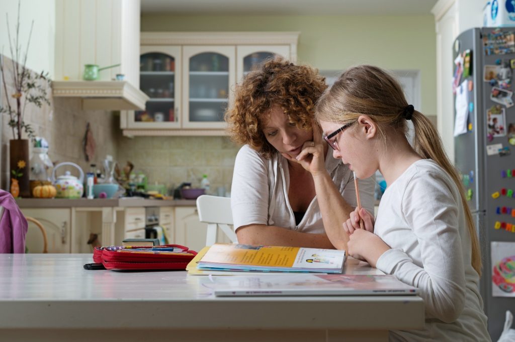 mother helping daughter with her homework at the table in the dining room