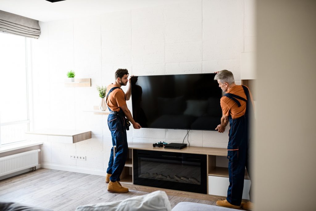 workers installing tv television on the wall indoors