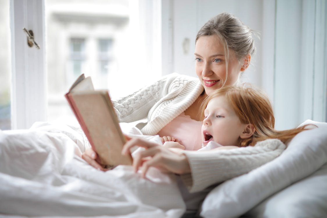 little girl with her mom reading in bed