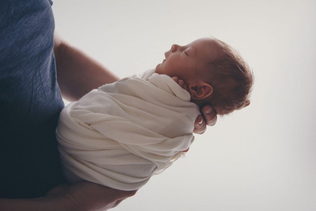 Newborn baby lying on hands of parents.