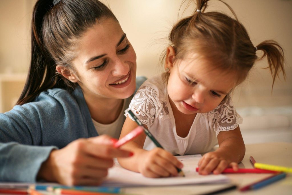 Mother helping her little girl to writing