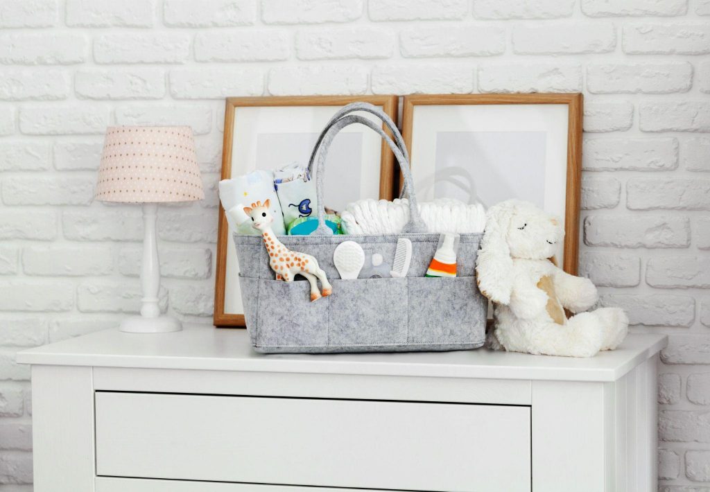 Mothers bag with toy, diapers and accessories on white background