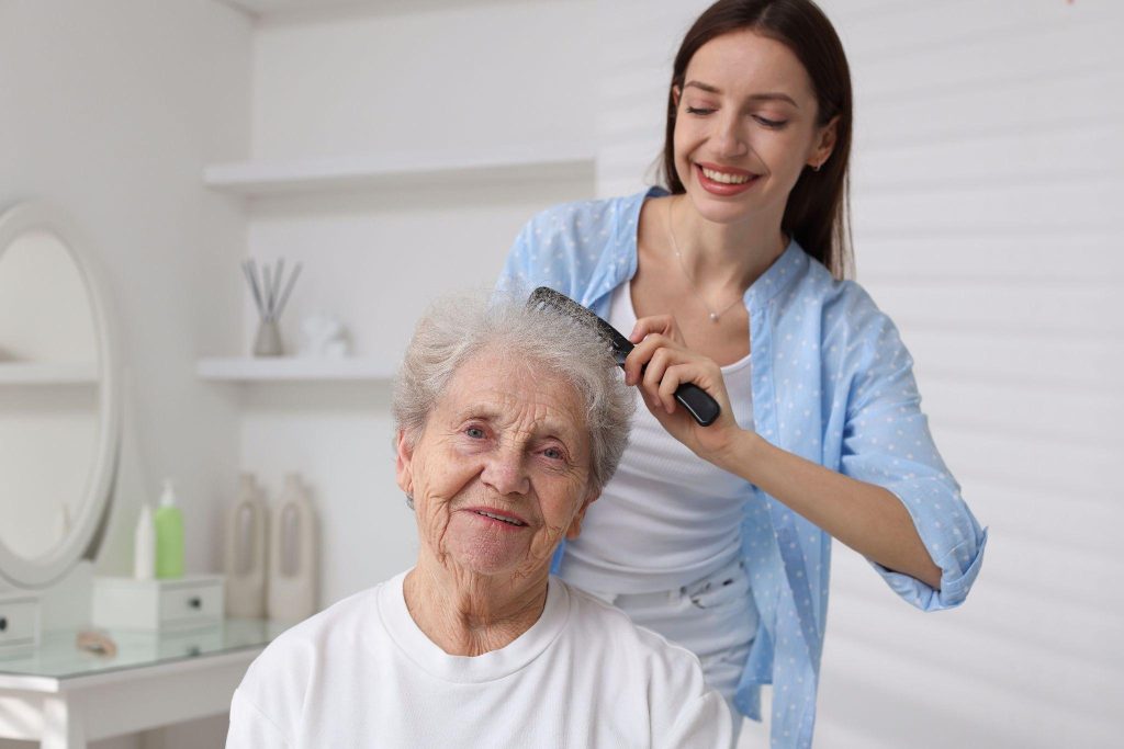 Caregiver brushing senior woman's hair, showing the personalized touch of concierge senior care.