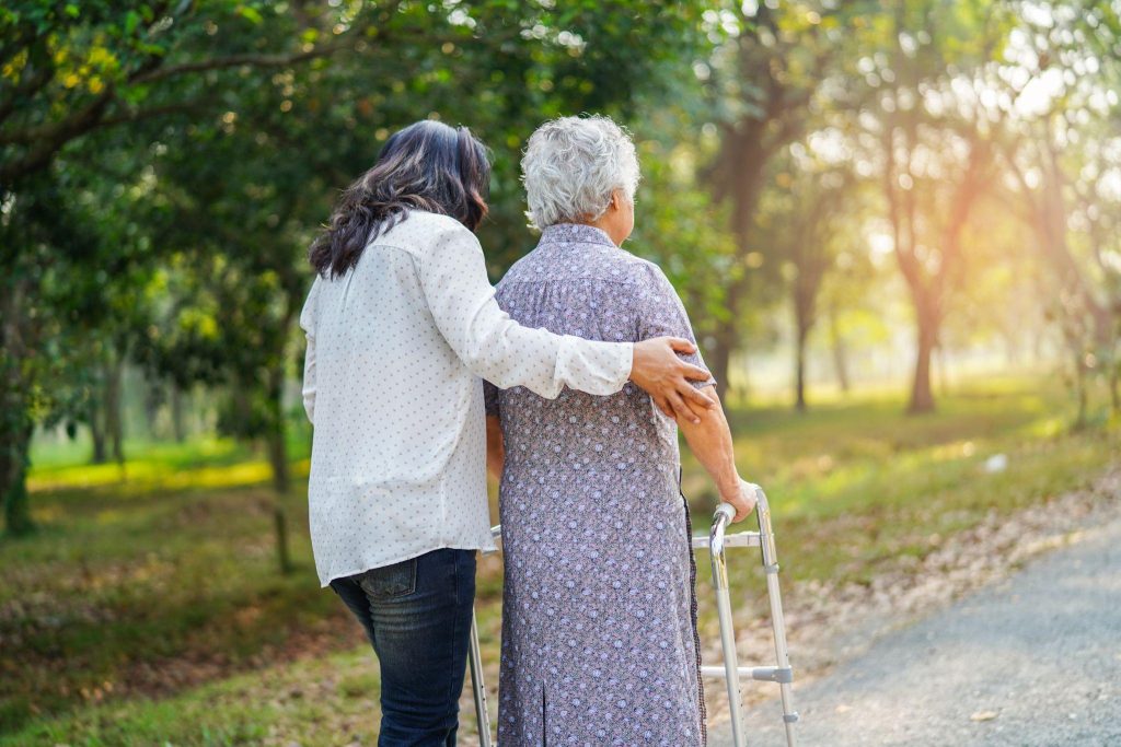 concierge caregiver walking with senior woman using a walker.